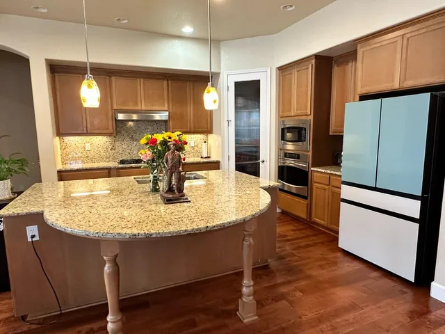 a kitchen with stainless steel appliances granite countertop a refrigerator a stove a sink and a refrigerator