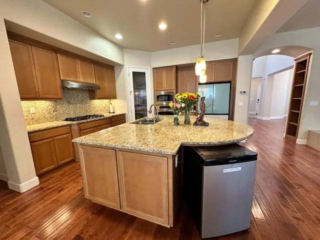 a kitchen with kitchen island granite countertop wooden floors and stainless steel appliances