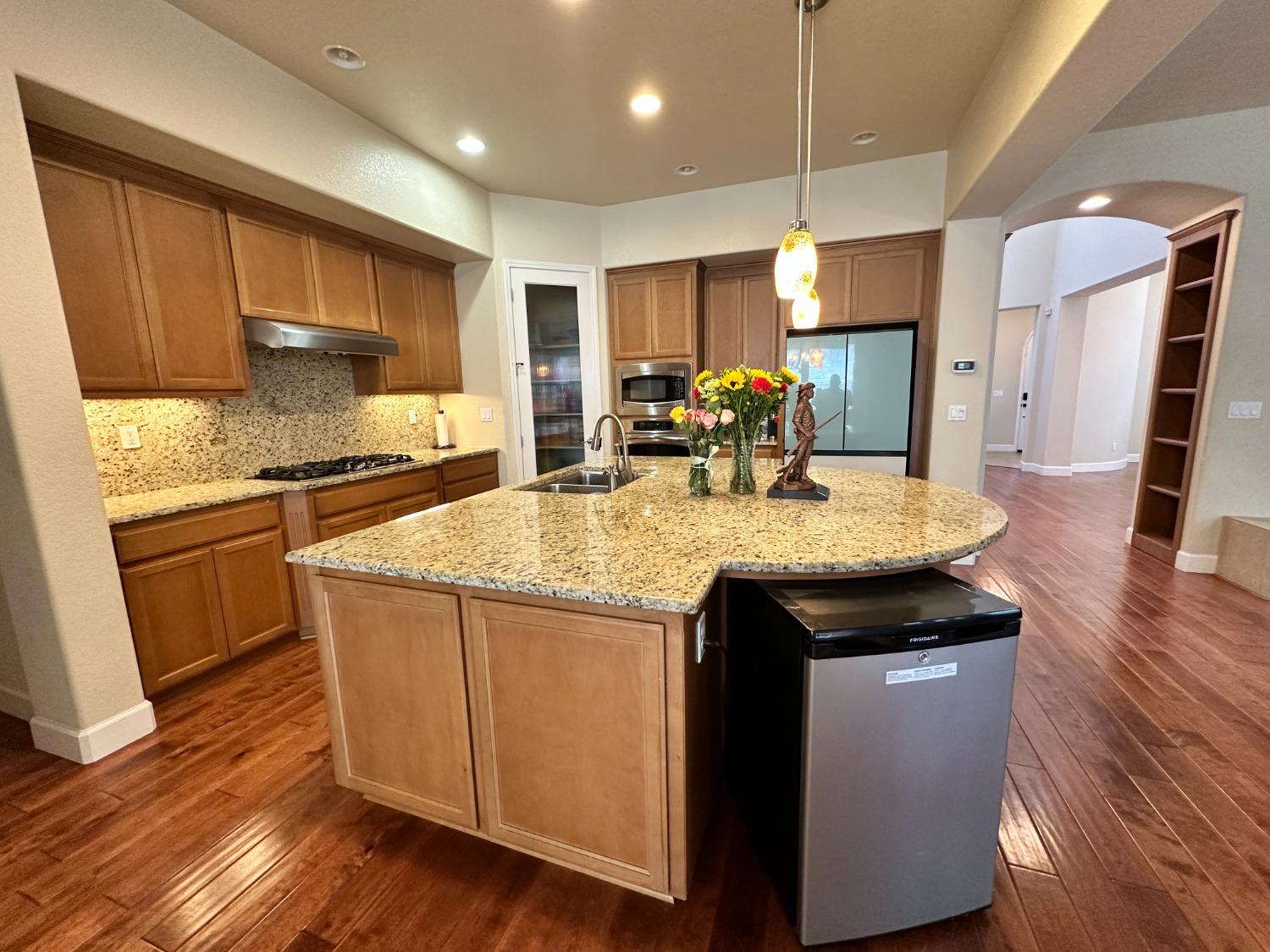 1040 Birch Run Way Manteca, CA 95336 - Photo 13 of 52 a kitchen with kitchen island granite countertop wooden floors and stainless steel appliances