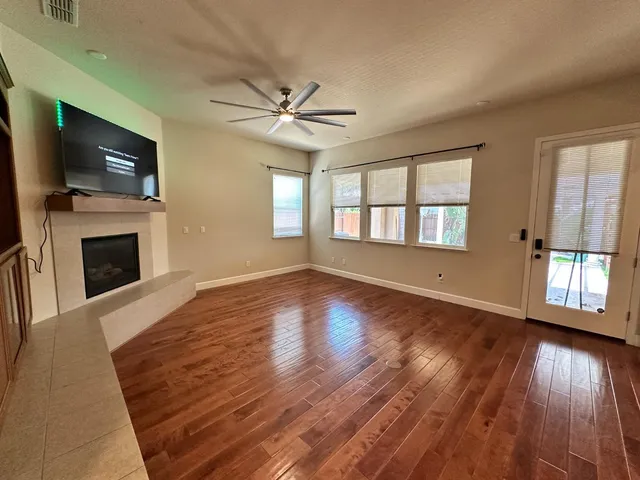 a view of a livingroom with wooden floor a fireplace and windows