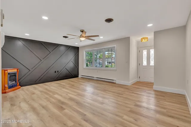 a view of an empty room with a window and wooden floor