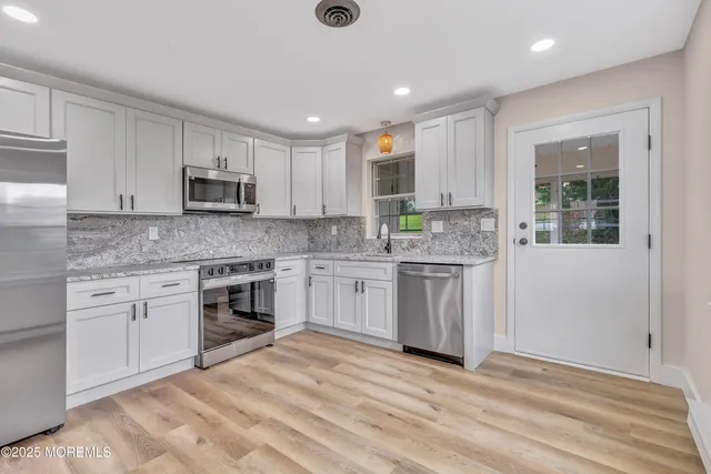 a kitchen with stainless steel appliances granite countertop a stove a sink and a microwave