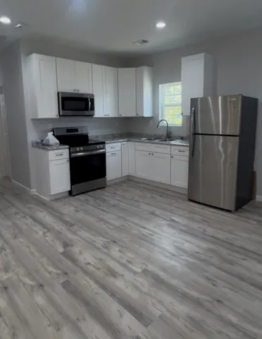 a kitchen with granite countertop white cabinets and stainless steel appliances