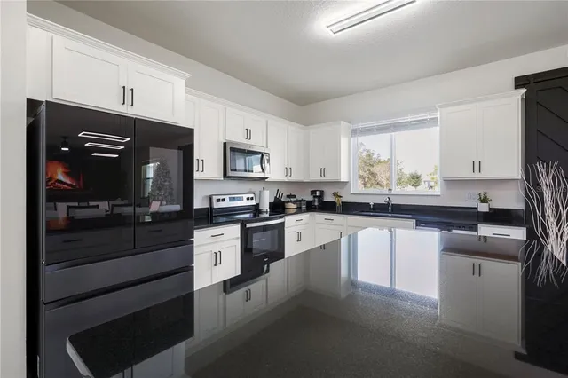 a kitchen with granite countertop white cabinets and stainless steel appliances