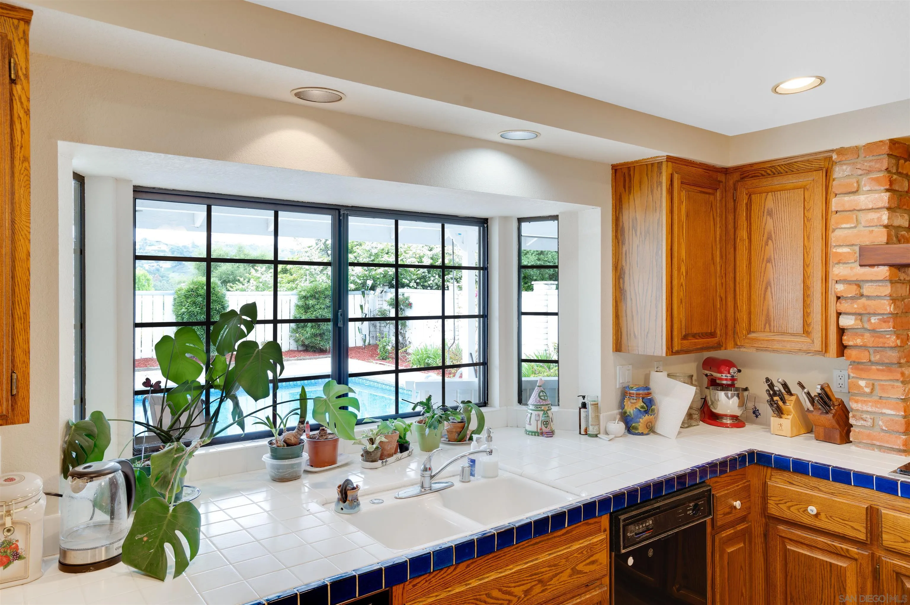3675 Northcliff Drive Fallbrook, CA 92028 - Photo 17 of 37 a view of a kitchen with kitchen island a large window cabinets a sink and living room view