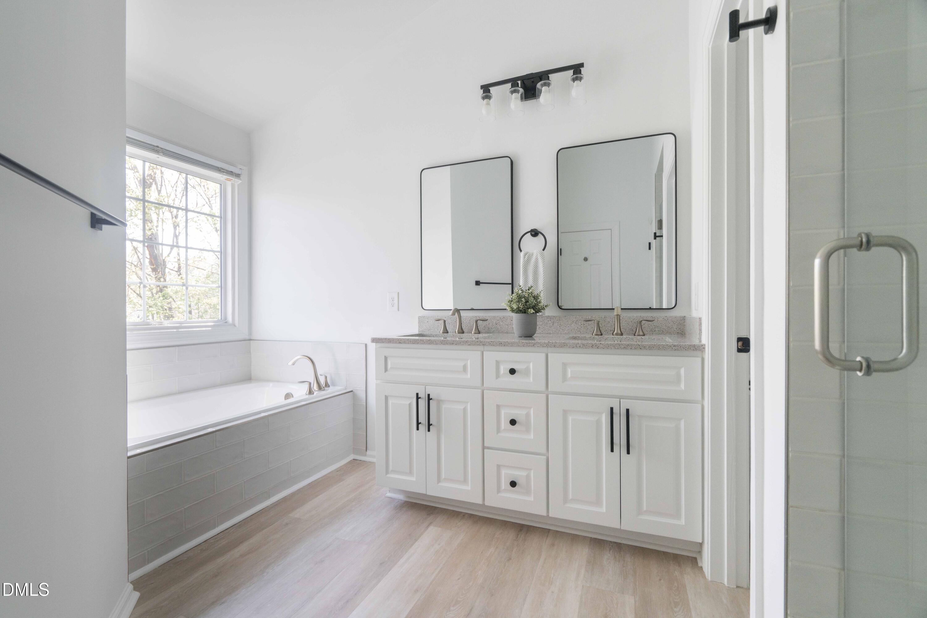 1512 Cooper Falls Lane Raleigh, NC 27614 - Photo 36 of 64 a bathroom with a double vanity sink a mirror and a bathtub