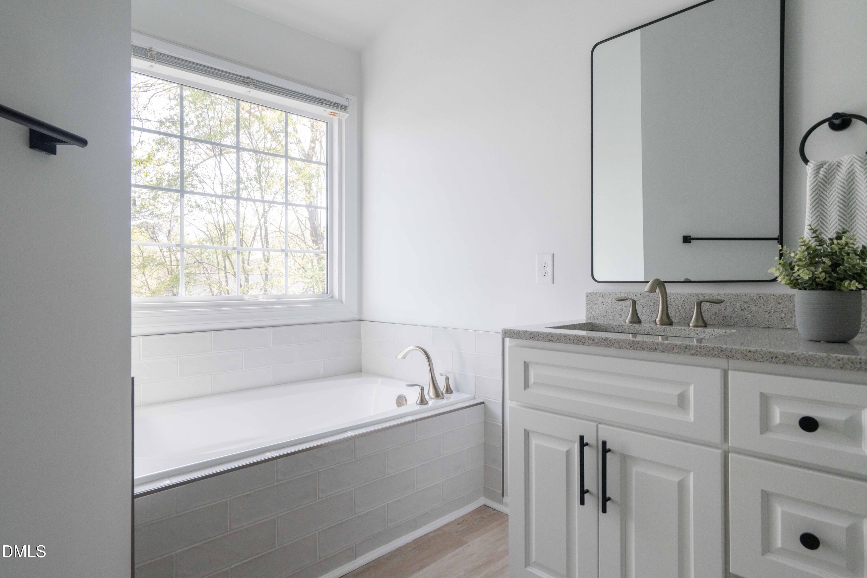 1512 Cooper Falls Lane Raleigh, NC 27614 - Photo 37 of 64 a bathroom with a granite countertop sink mirror and a bathtub