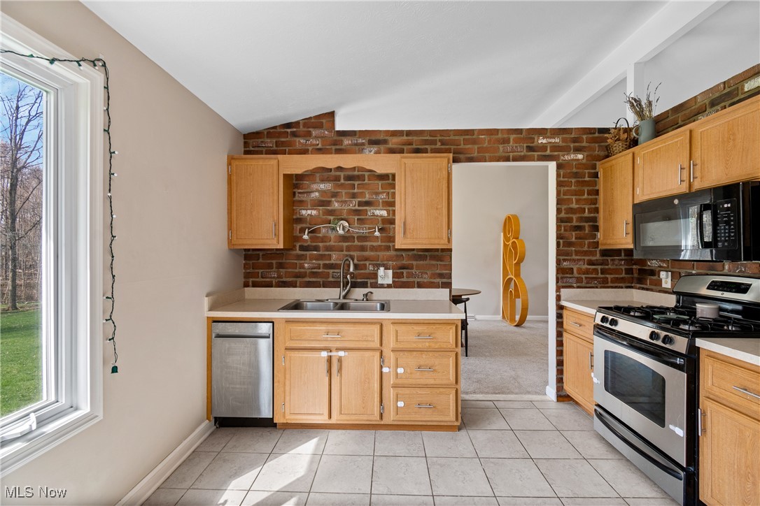 96 Spring Creek Road Northfield, OH 44067 - Photo 14 of 36 Kitchen featuring vaulted ceiling, light countertops, light tile patterned flooring, appliances with stainless steel finishes, and a sink