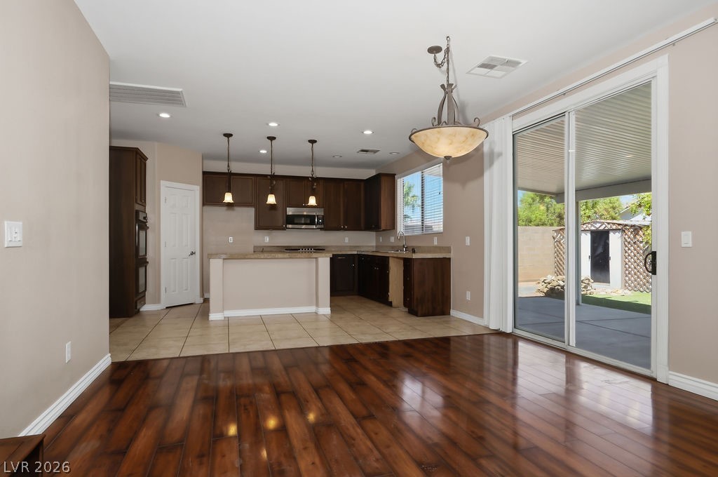 9712 North Running Rabbit Street Las Vegas, NV 89143 - Photo 3 of 42 Rich hardwood floors complement the open-concept kitchen and dining area with seamless outdoor access.