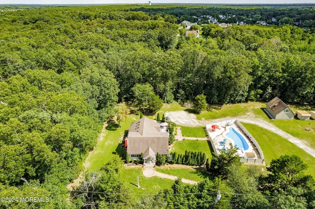 an aerial view of residential house with outdoor space and trees all around