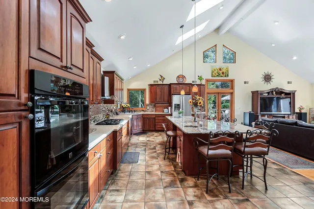 a living room with stainless steel appliances kitchen island granite countertop a stove and a refrigerator