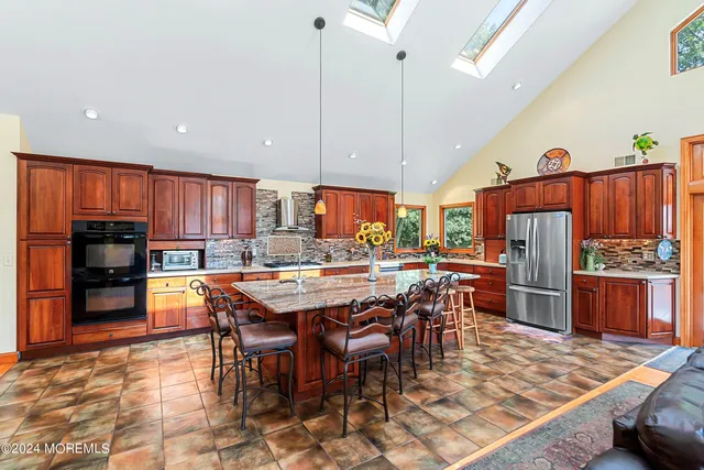 a view of a kitchen with kitchen island stainless steel appliances refrigerator stove dining table and chairs