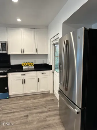 a kitchen with stainless steel appliances a refrigerator and white cabinets