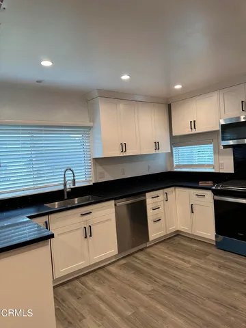 a kitchen with granite countertop a sink a stove top oven and cabinets