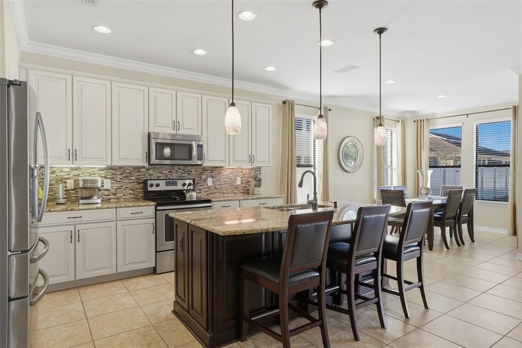 1154 Fountain Coin Loop Orlando, FL 32828 - Photo 11 of 48 a kitchen with stainless steel appliances granite countertop a stove top oven a sink dishwasher a dining table and chairs