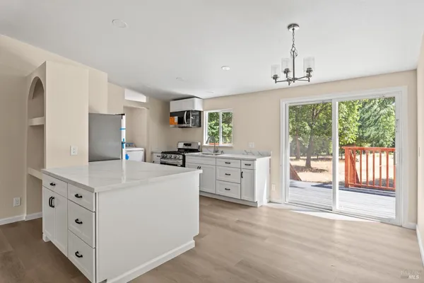 a large white kitchen with granite countertop a stove oven and a sink with granite countertops