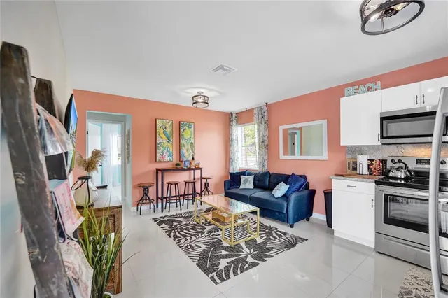 a living room with furniture a flat screen tv and a refrigerator