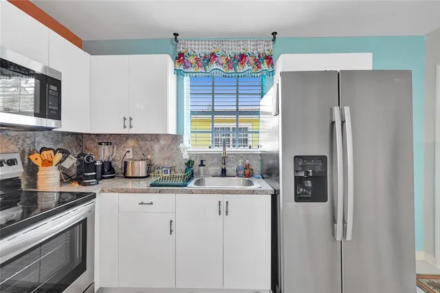 a kitchen with stainless steel appliances granite countertop a refrigerator sink and stove