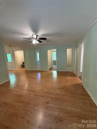 a view of an empty room with kitchen and window