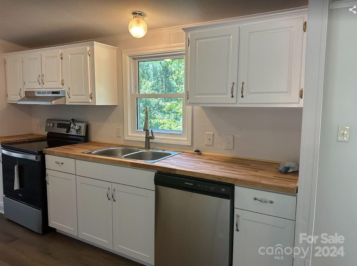 1770 Dark Corner Road Rutherfordton, NC 28139 - Photo 6 of 26 a kitchen with stainless steel appliances granite countertop a sink a stove and white cabinets with wooden floor