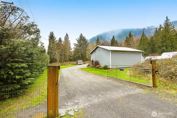 a view of a house with backyard and trees in the background