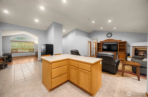 a large living room with stainless steel appliances granite countertop couches a flat screen tv and a refrigerator