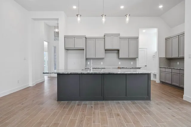 a kitchen with kitchen island granite countertop wooden cabinets and a sink