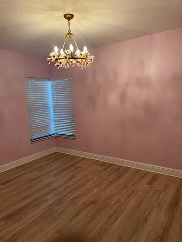 a view of room with wooden floor and chandelier