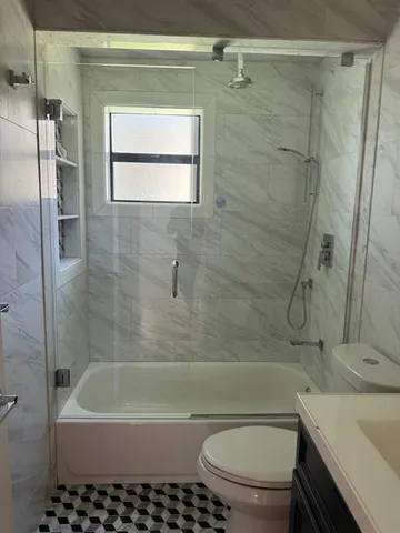 a bathroom with a granite countertop bathtub shower sink vanity and toilet