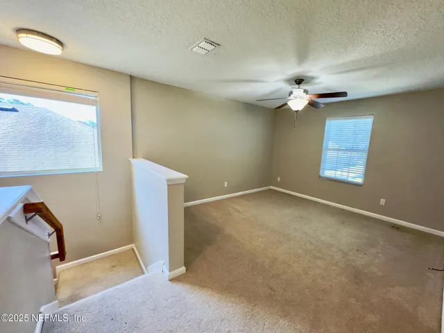 an empty room with windows and fan
