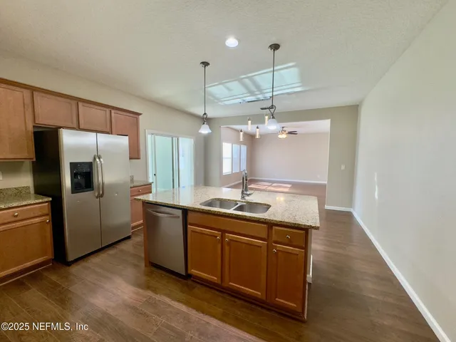 a kitchen with stainless steel appliances granite countertop a sink a refrigerator and a counter top space
