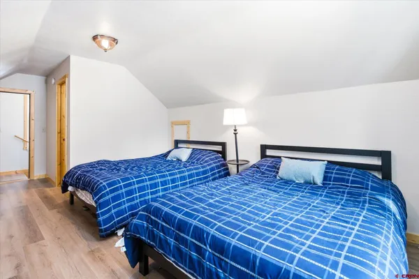 a bedroom with two beds and wooden floor