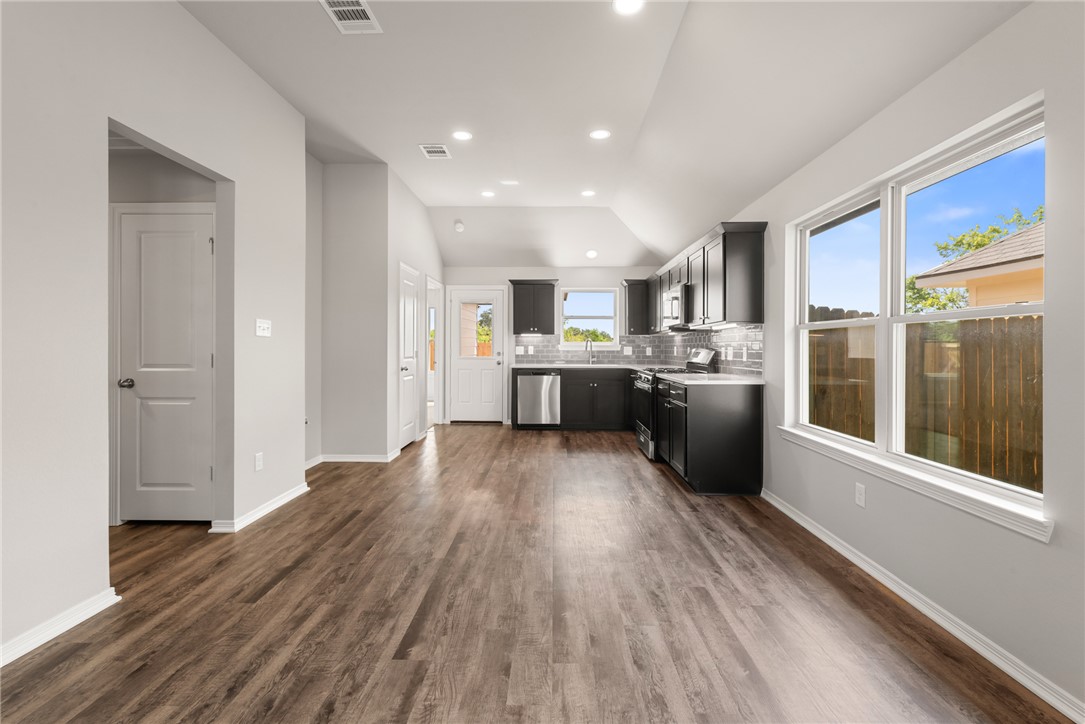 2869 Messenger Way Bryan, TX 77803 - Photo 6 of 23 a kitchen with stainless steel appliances a refrigerator a sink dishwasher a oven with wooden cabinets and wooden floor
