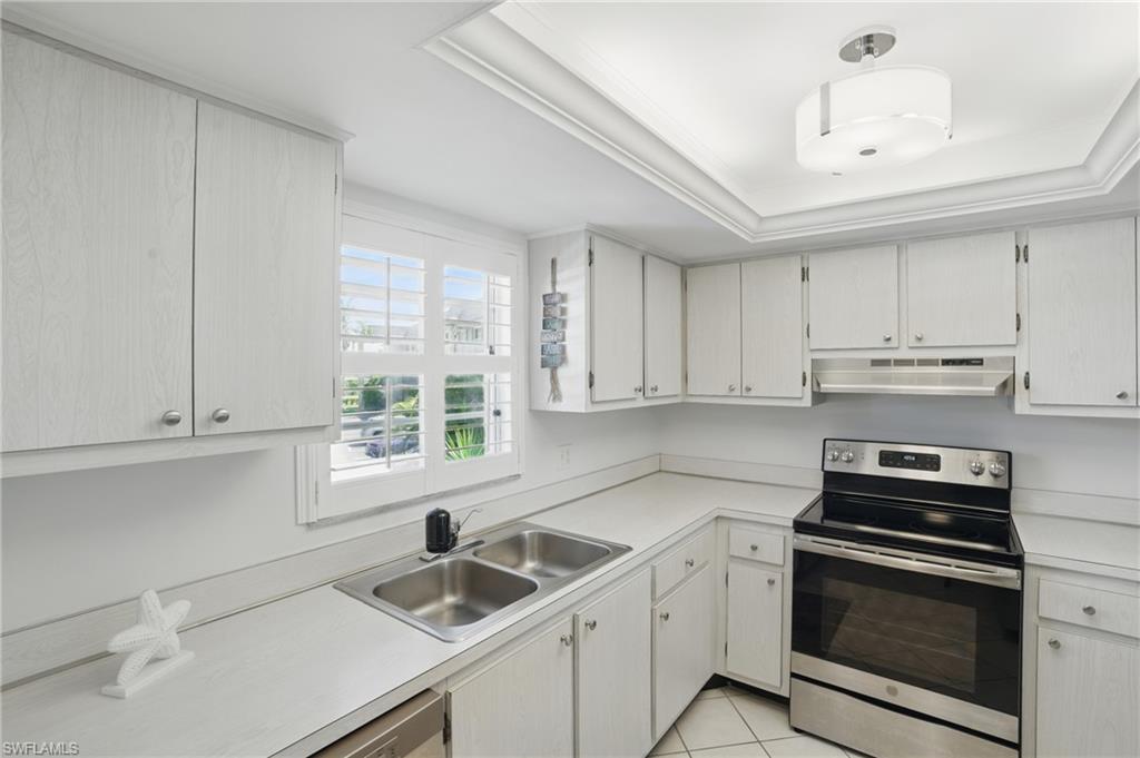 5435 Rattlesnake Hammock Road, Unit E202 Naples, FL 34113 - Photo 5 of 25 a kitchen with a sink stove top oven and cabinets