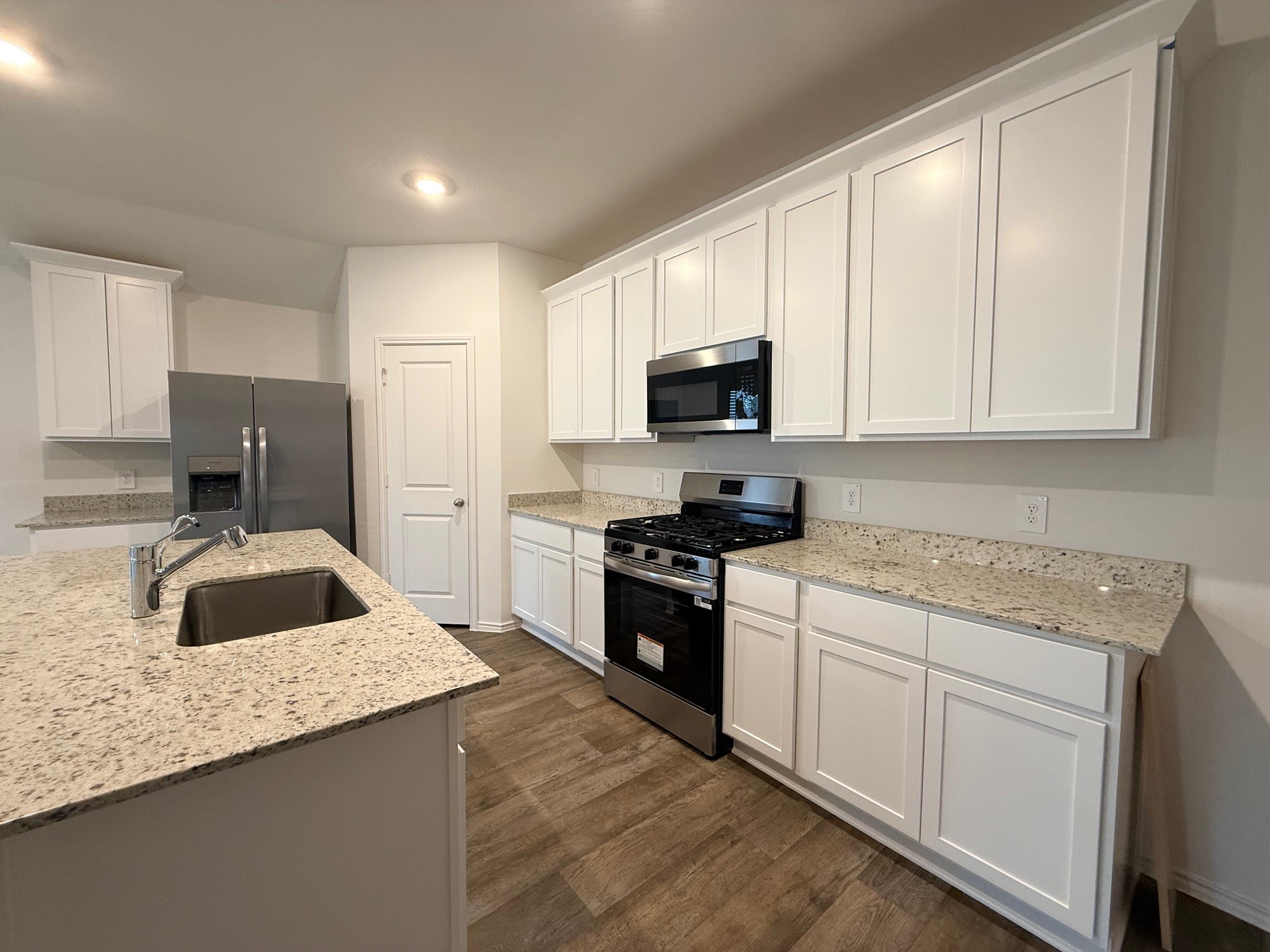 3807 Axyl Run Fulshear, TX 77423 - Photo 4 of 29 a kitchen with granite countertop white cabinets and stainless steel appliances
