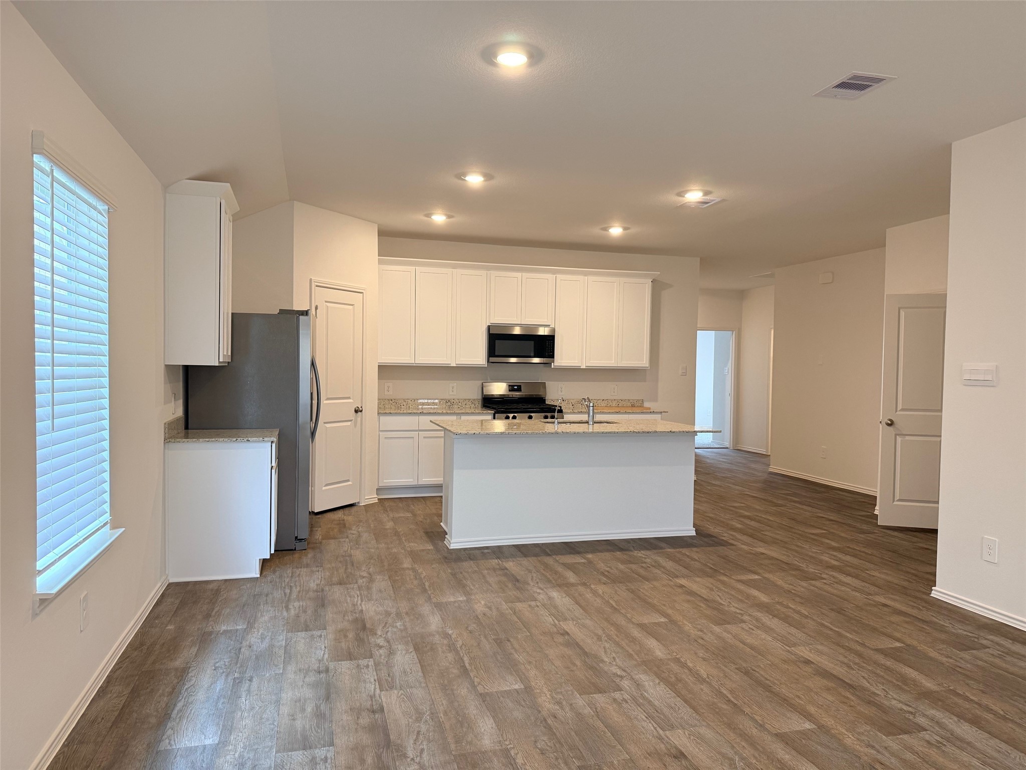 3807 Axyl Run Fulshear, TX 77423 - Photo 5 of 29 a kitchen with stainless steel appliances granite countertop a stove a refrigerator a sink and white cabinets with wooden floor