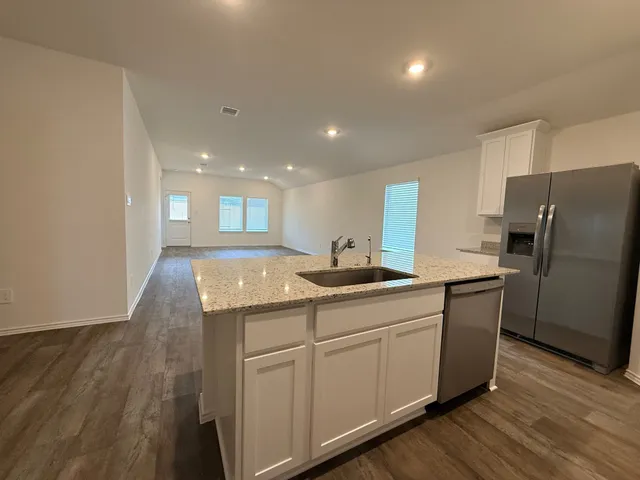 a kitchen with stainless steel appliances granite countertop a sink a stove a refrigerator and cabinets with wooden floor