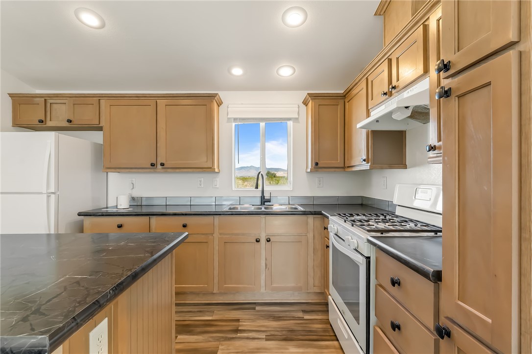 3534 Eloy Road Golden Valley, AZ 86413 - Photo 14 of 58 Kitchen featuring white appliances, under cabinet range hood, light wood-style floors, recessed lighting, and light brown cabinetry