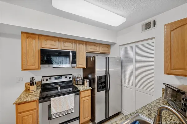 a kitchen with stainless steel appliances granite countertop a refrigerator and a stove top oven