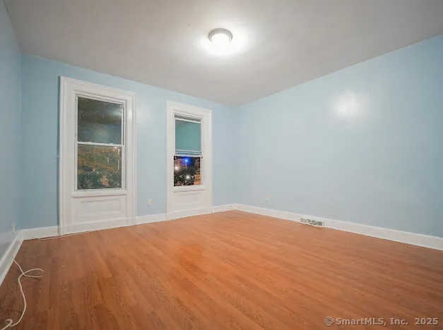 a view of an empty room with wooden floor and a window