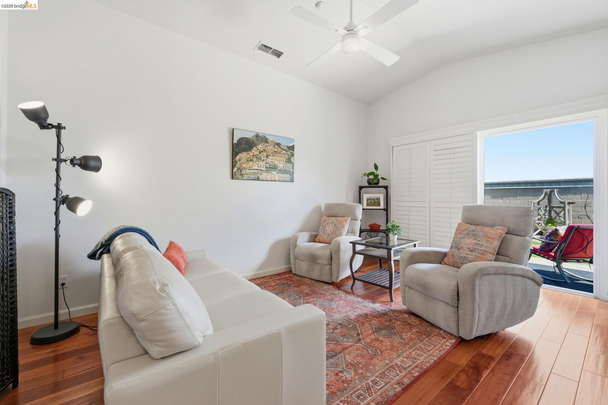 1024 Diamante Rio Vista, CA 94571 - Photo 4 of 27 Vaulted ceiling with a white ceiling fan, wood-finish flooring, and sliding glass doors with interior plantation shutters leading to an outdoor patio