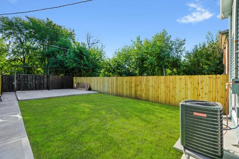 a view of a backyard with a large tree and wooden fence