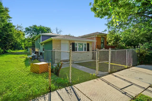 a backyard of a house with table and chairs potted plants and large tree