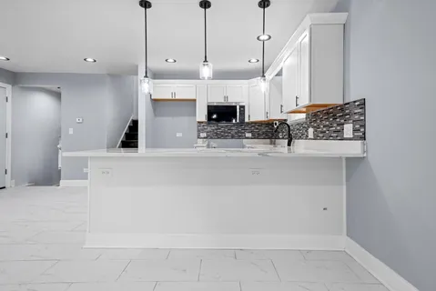 a large white kitchen with a large island in the center