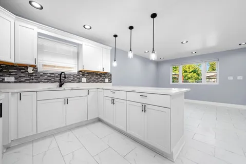 a kitchen with white cabinets and window