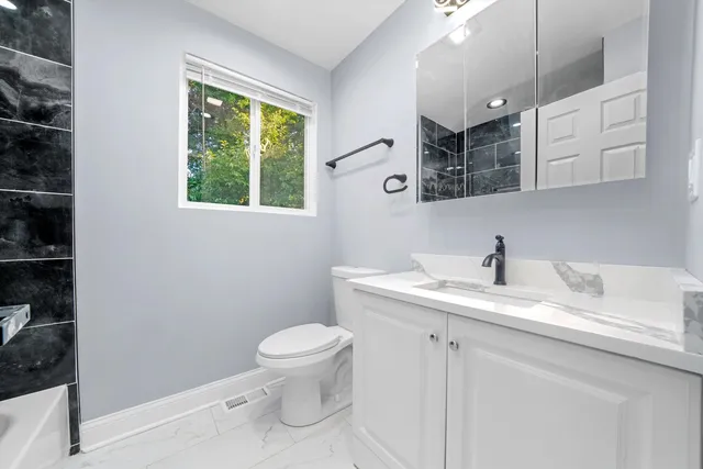 a bathroom with a granite countertop sink mirror vanity and toilet