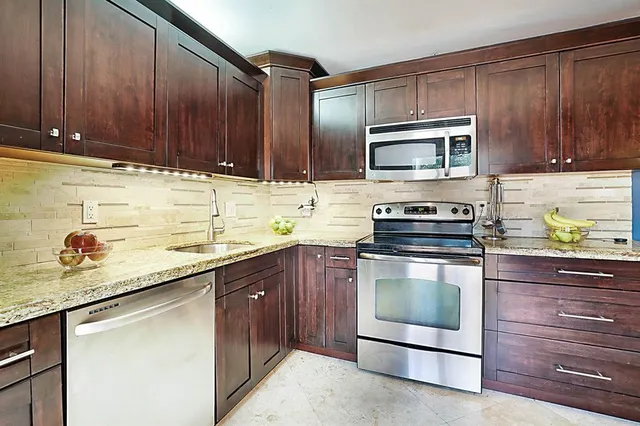 a kitchen with stainless steel appliances granite countertop wooden cabinets a stove top oven a sink and dishwasher