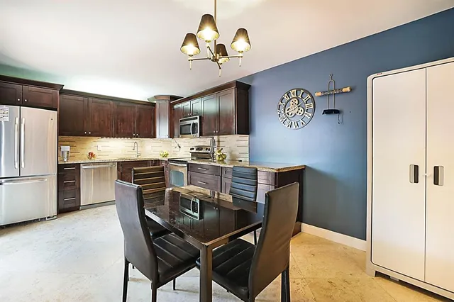 a kitchen with stainless steel appliances a refrigerator a stove a microwave a dining table and chairs with wooden floor