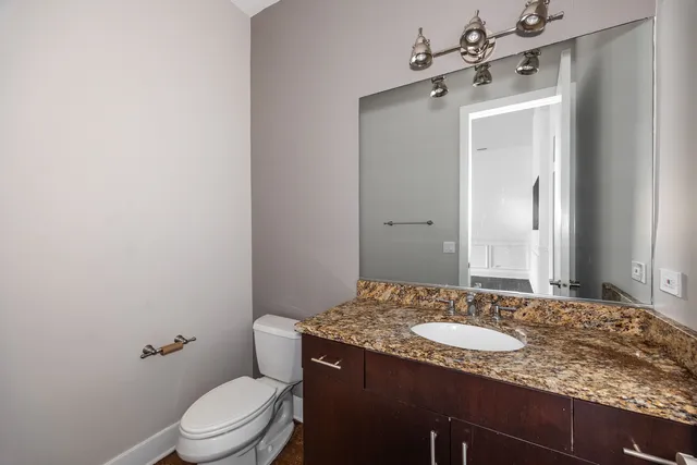 a bathroom with a granite countertop sink toilet and mirror