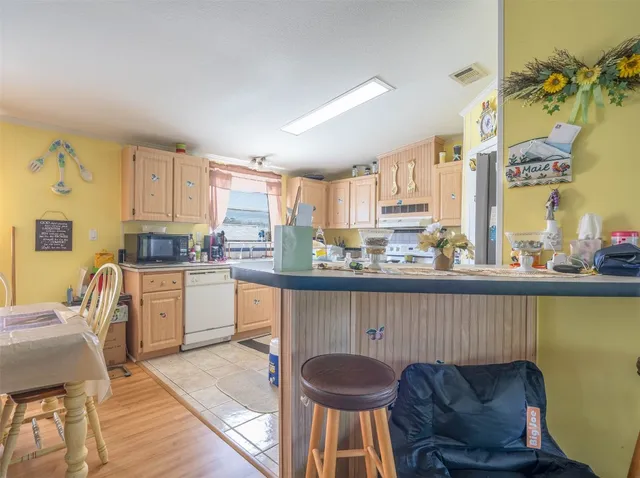 a kitchen with granite countertop a table chairs stove top oven and sink